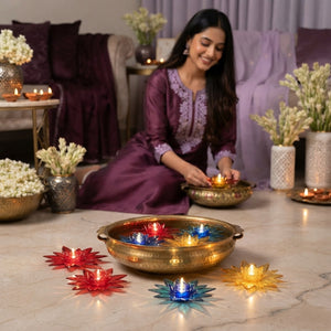 An Indian woman placing a lotus-shaped water sensor diya into a decorative bowl in a softly lit living room.