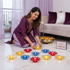 An Indian woman placing glowing lotus-shaped water sensor diyas on a table in a modern living room with lavender and plum dec